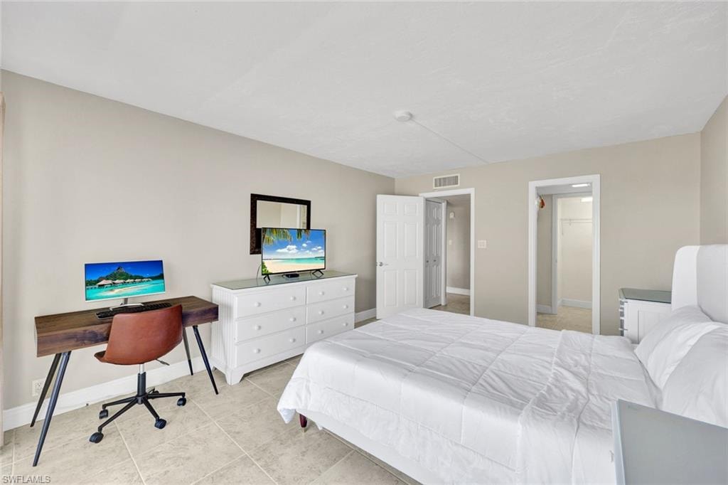 Bedroom featuring a spacious closet, a desk, and light tile patterned floors