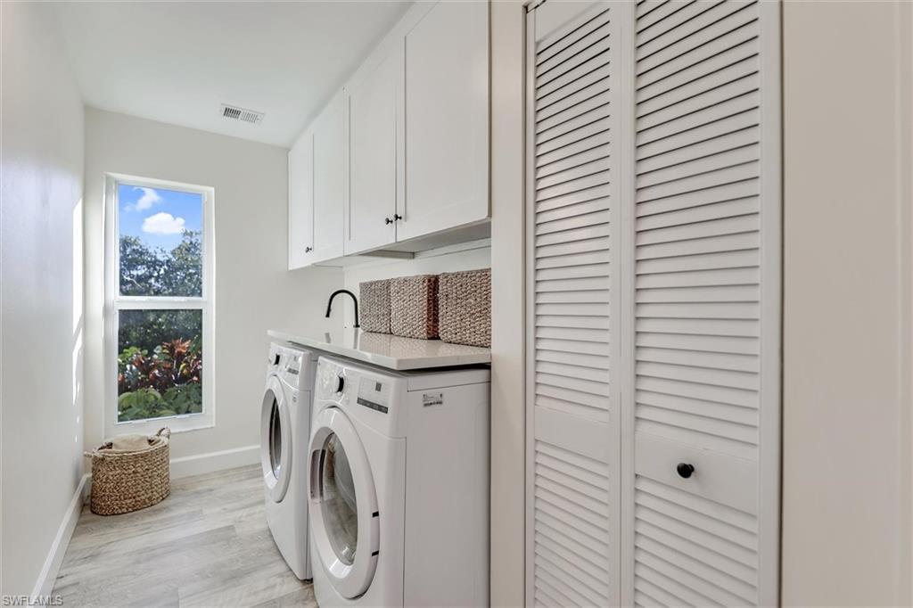 Laundry area with cabinet space, light wood finished floors, and washing machine and dryer