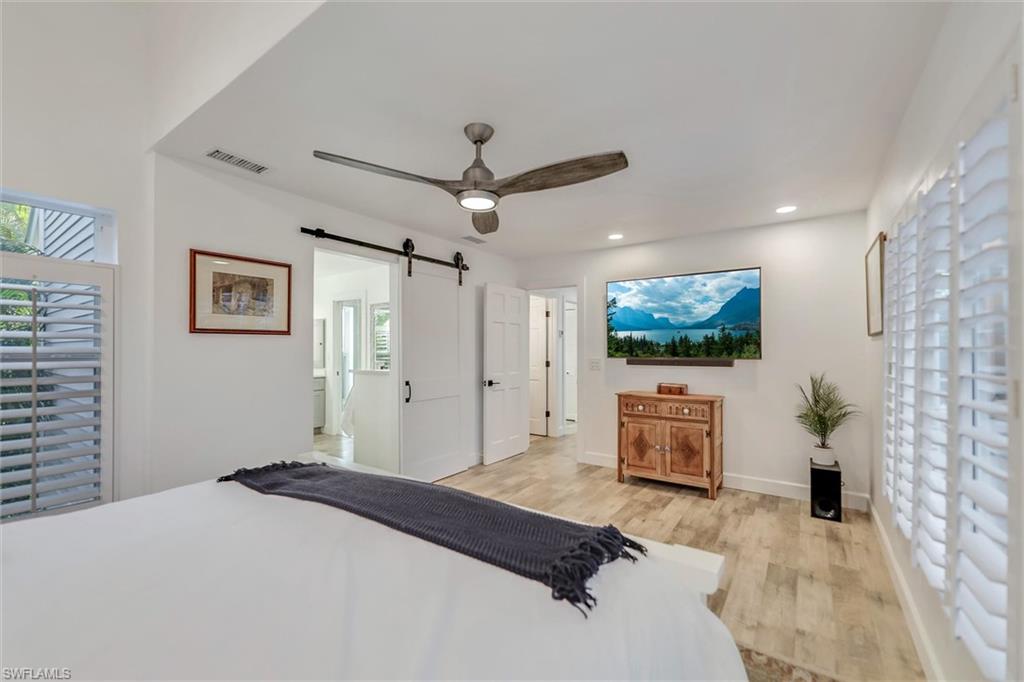 Bedroom featuring multiple windows, a barn door, light wood finished floors, ceiling fan, and recessed lighting