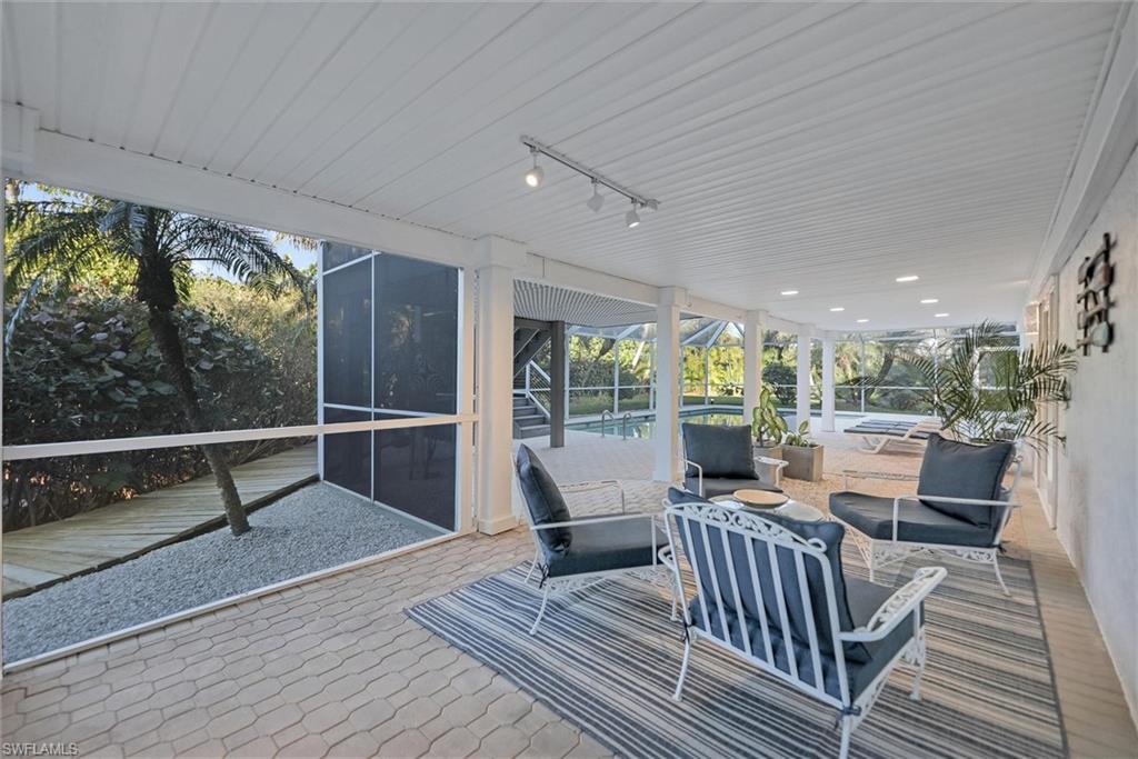 Sunroom featuring rail lighting, an outdoor lounge area, and a patio