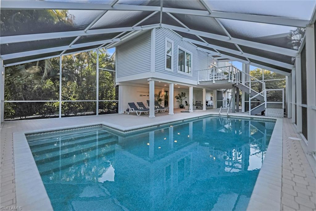 Outdoor pool featuring a sunroom, glass enclosure, and a patio area