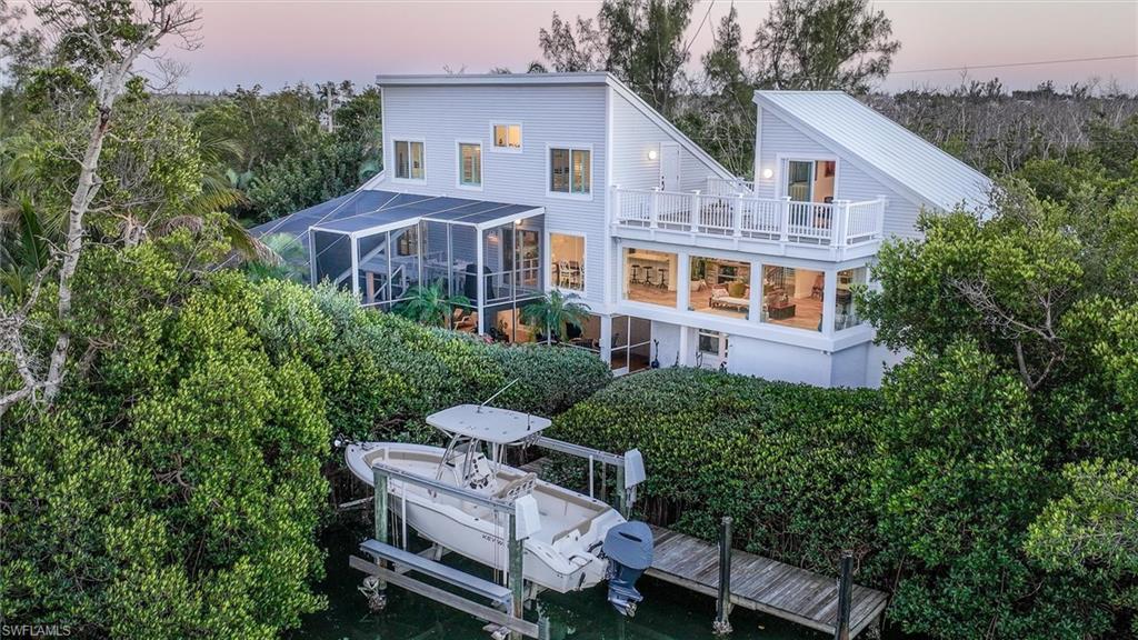 Rear view of house featuring boat lift, a lanai, and a sunroom