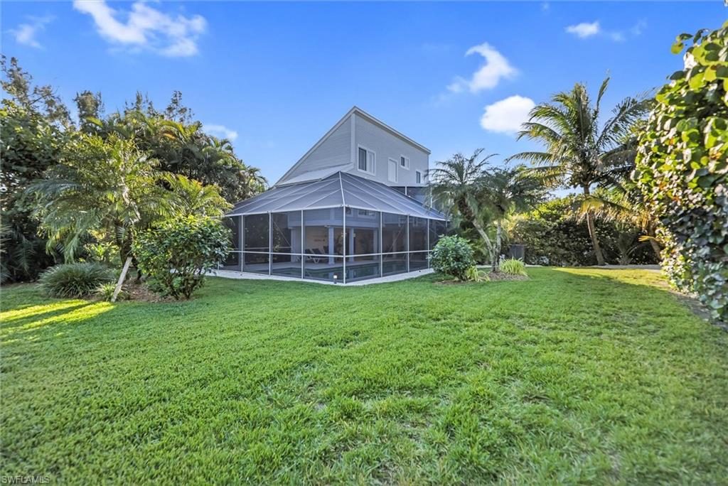 Back of house featuring glass enclosure, a lawn, and a sunroom
