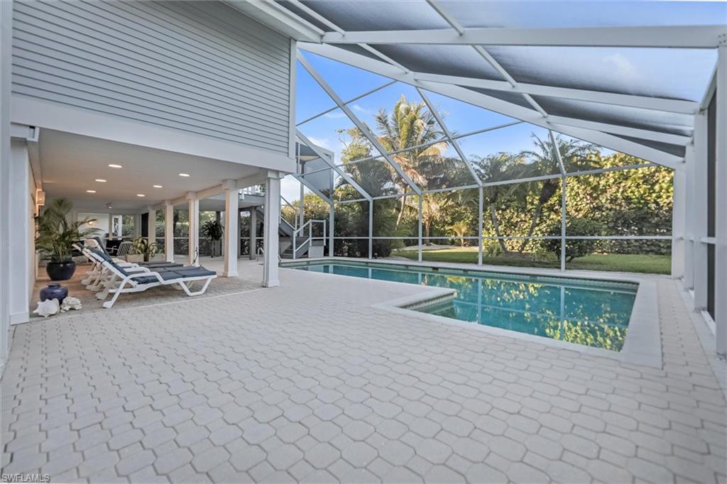 Swimming pool featuring a patio, a sunroom, and glass enclosure