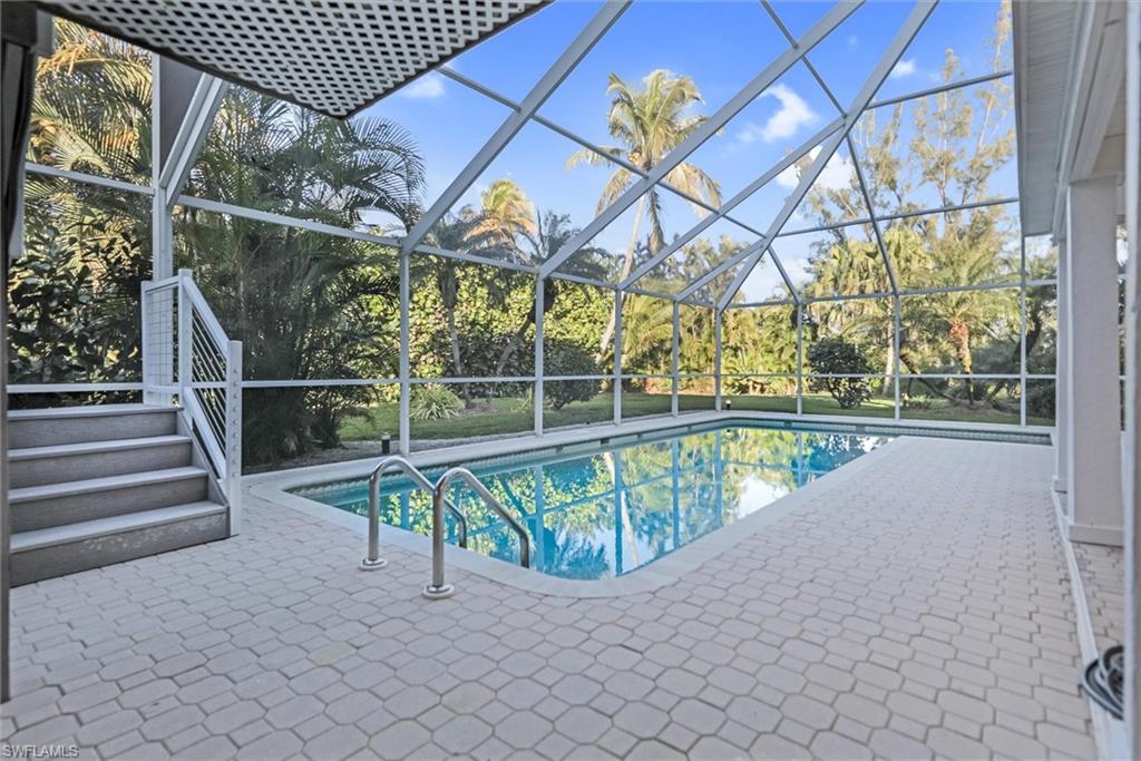 Swimming pool featuring a sunroom, a patio area, and glass enclosure