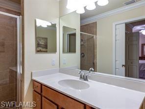 Bathroom with crown molding, vanity, and an enclosed shower