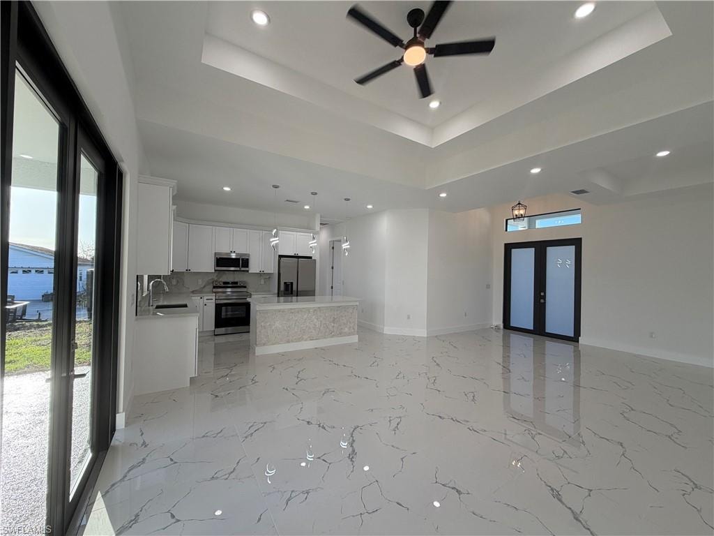 Unfurnished living room featuring french doors, recessed lighting, a ceiling fan, and light marble finish floors
