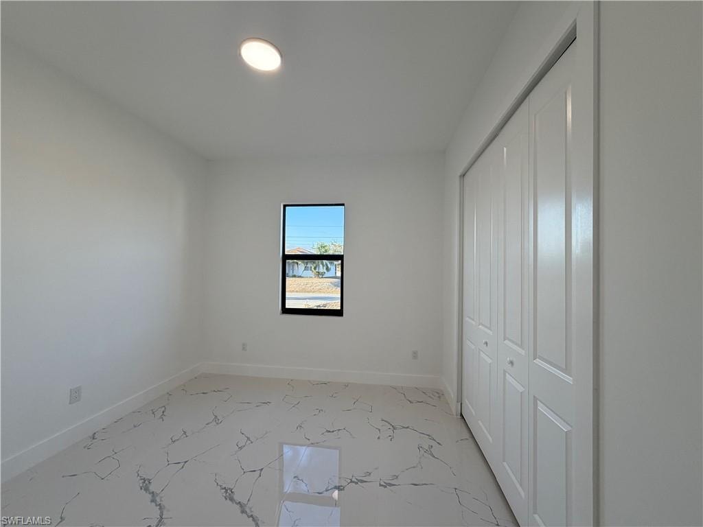 Unfurnished bedroom with a closet and light marble finish floors