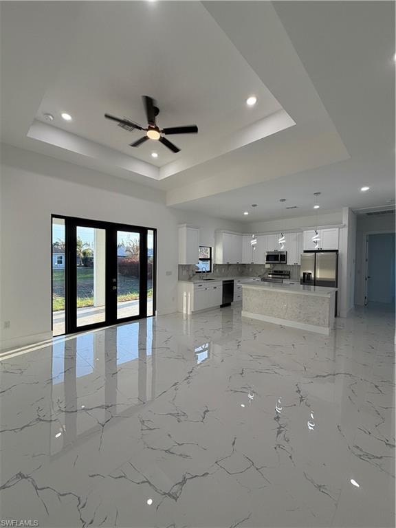 Unfurnished living room with ceiling fan, french doors, recessed lighting, and a raised ceiling