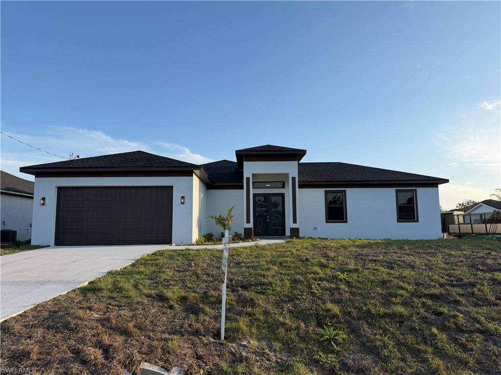 Prairie-style house featuring a garage, driveway, stucco siding, and a front yard