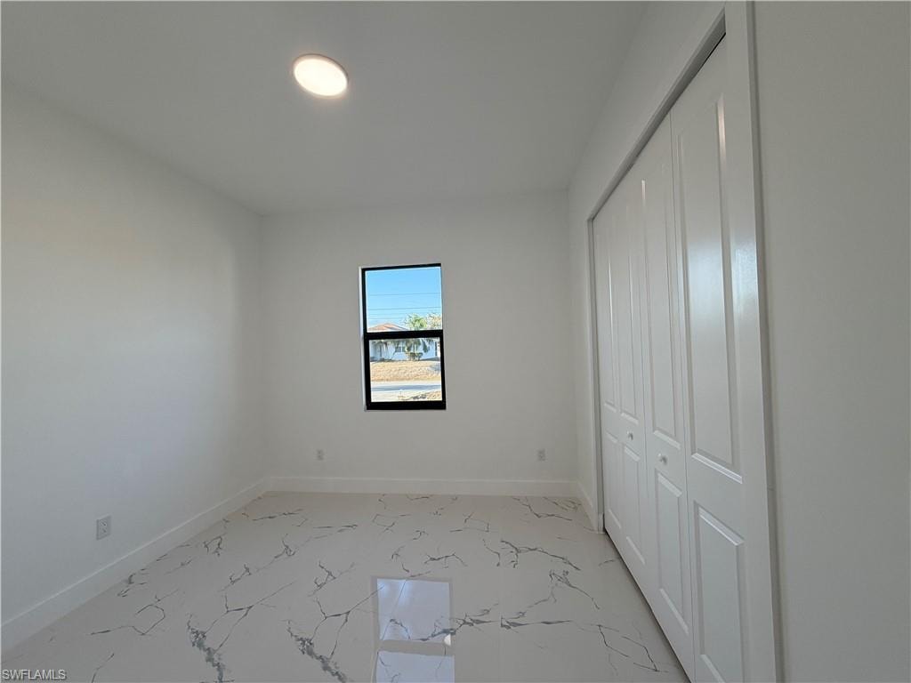 Unfurnished bedroom featuring a closet and light marble finish floors