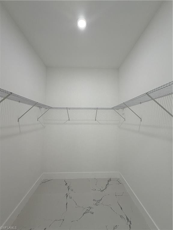 Walk in closet with light marble finish floors