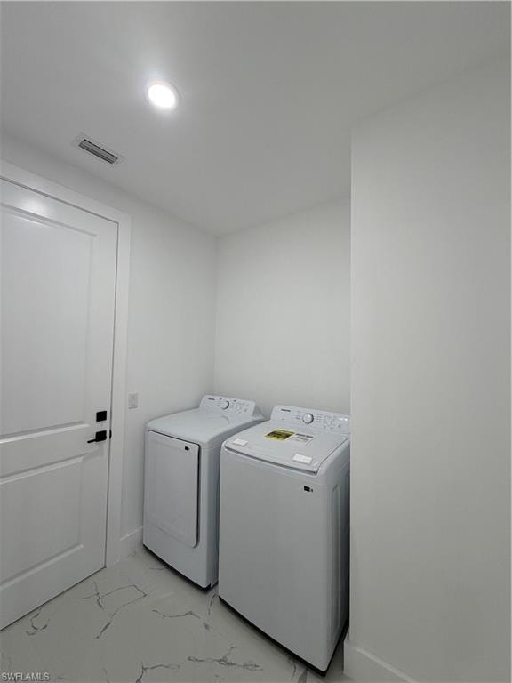 Laundry area with light marble finish floors, washing machine and clothes dryer, and recessed lighting