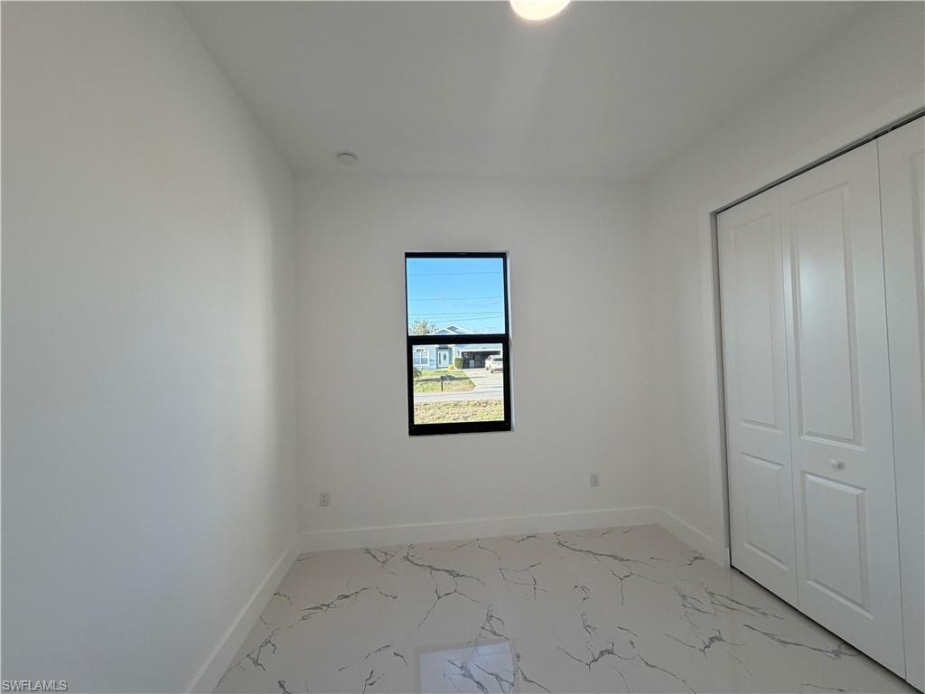Unfurnished bedroom featuring light marble finish flooring and a closet