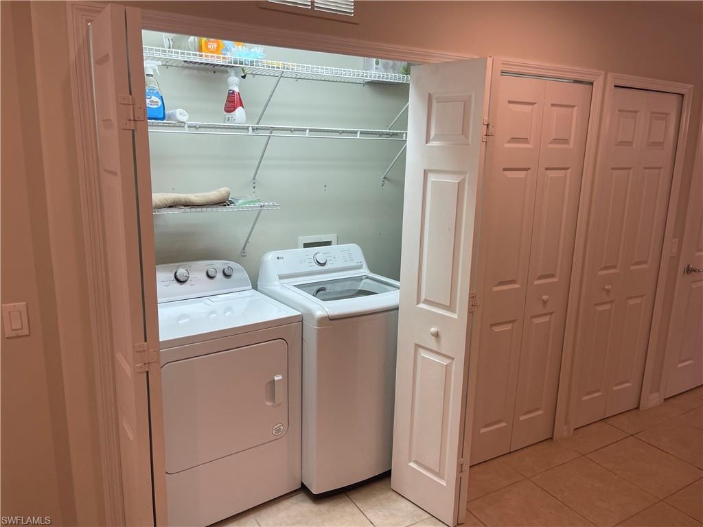 Laundry area with washer and dryer and light tile patterned flooring
