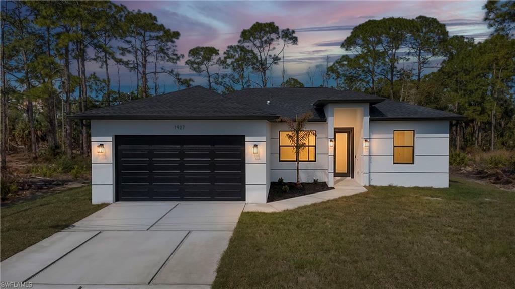 View of front of home featuring a front lawn, concrete driveway, a garage, a shingled roof, and stucco siding
