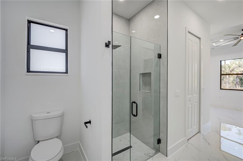 Full bathroom with a stall shower, recessed lighting, light marble finish flooring, and a ceiling fan