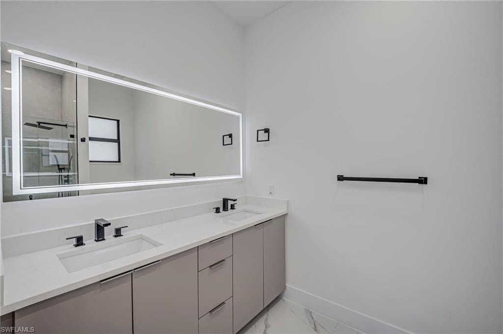 Full bathroom with double vanity and light marble finish flooring