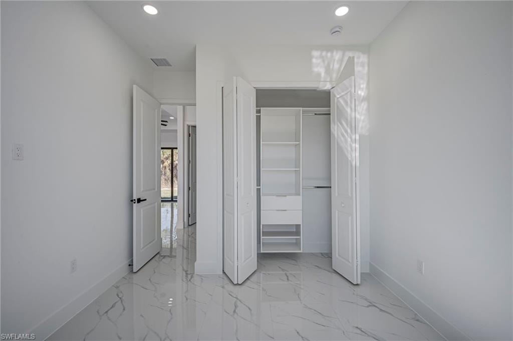 Unfurnished bedroom featuring recessed lighting, a closet, and light marble finish flooring