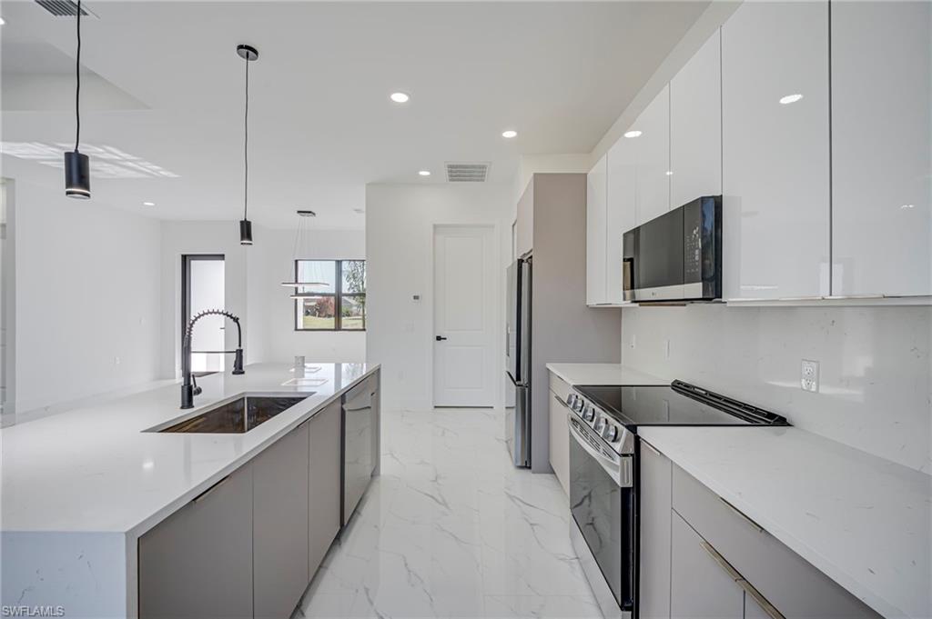 Kitchen featuring stainless steel appliances, light stone countertops, a large island, modern cabinets, and light marble finish floors