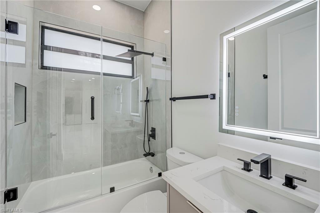Bathroom featuring vanity and bath / shower combo with glass door