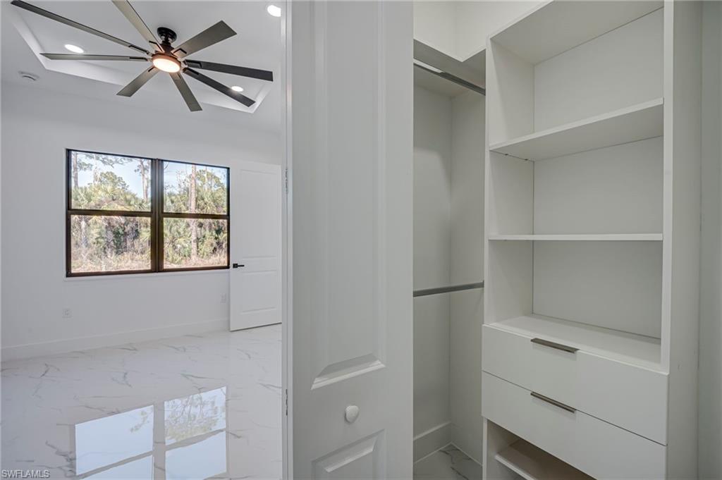 Walk in closet featuring light marble finish floors and ceiling fan