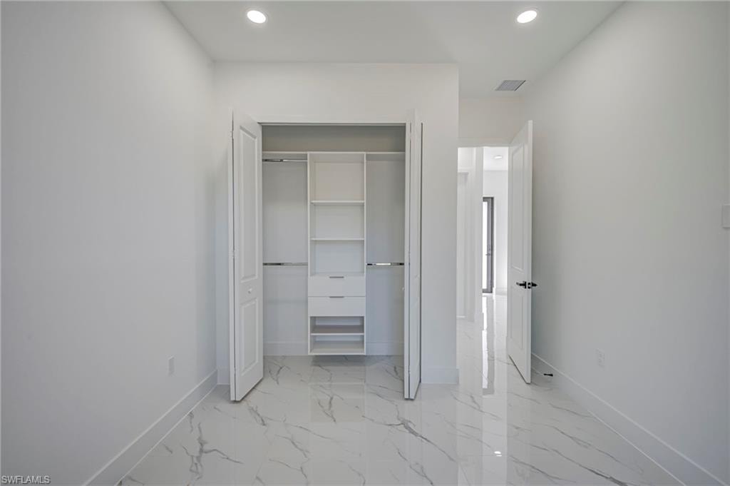 Unfurnished bedroom with recessed lighting, light marble finish floors, and a closet