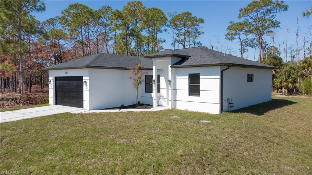 View of front of home with a front lawn, a garage, roof with shingles, stucco siding, and concrete driveway