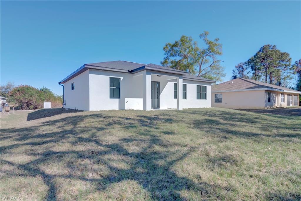 Rear view of house with a patio area, a yard, and stucco siding