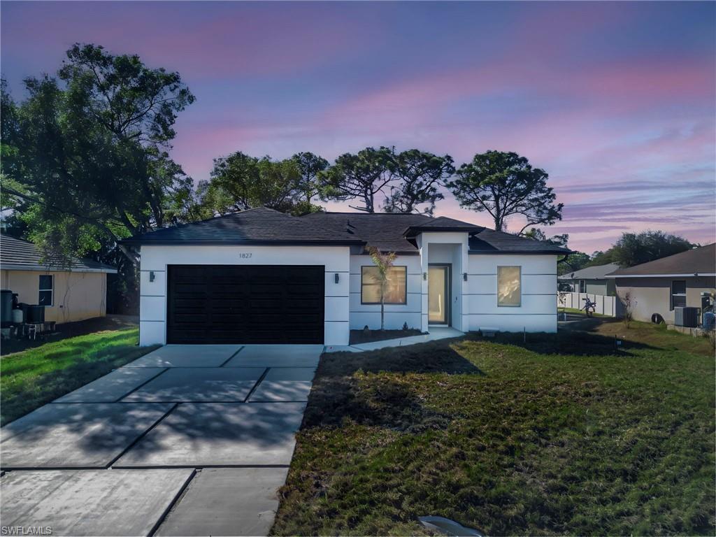 Ranch-style house featuring a front yard, an attached garage, driveway, and stucco siding