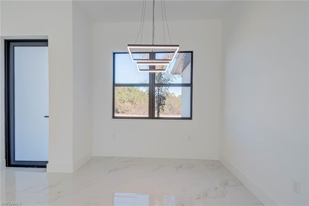 Unfurnished dining area featuring marble tiled flooring and baseboards