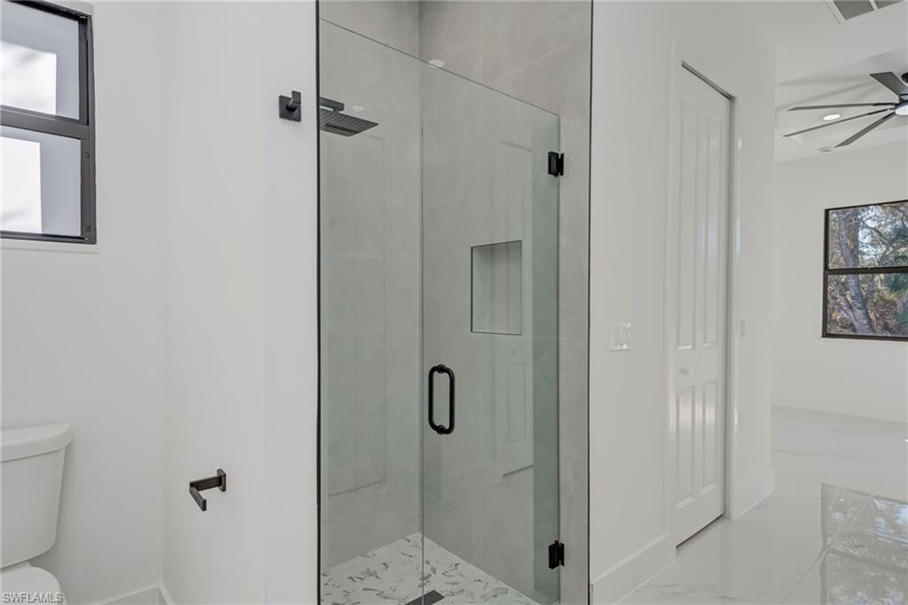 Full bath featuring a stall shower, a ceiling fan, and marble finish floors