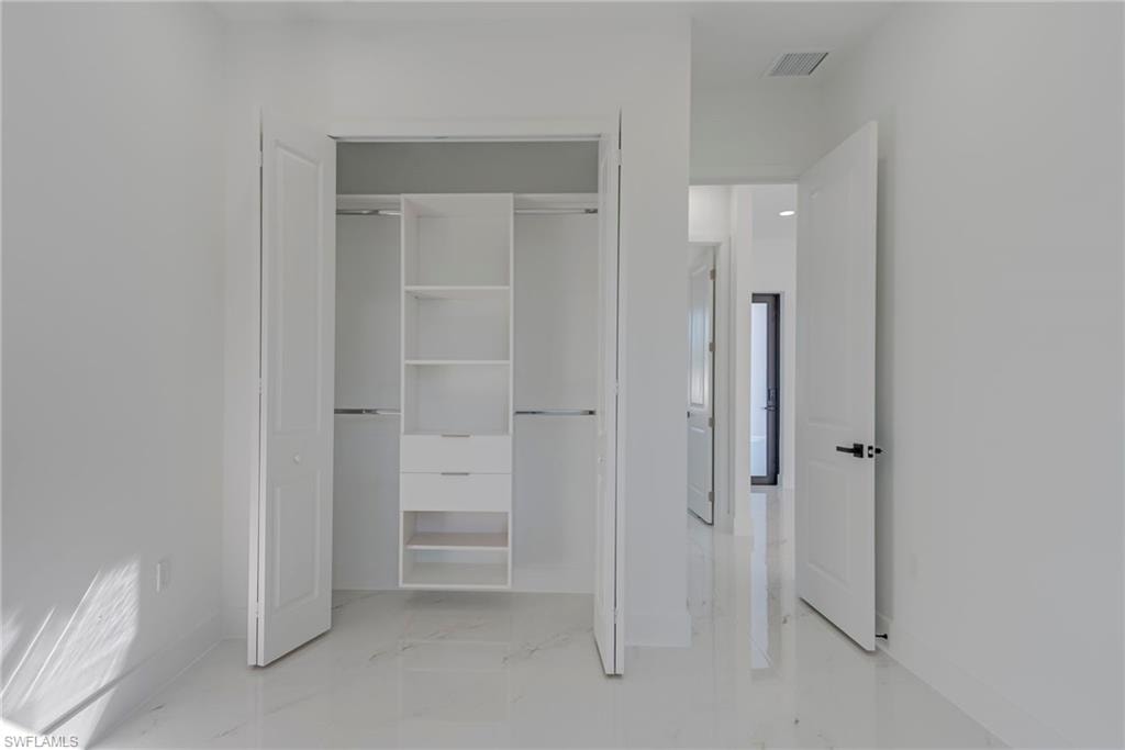 Unfurnished bedroom featuring a closet and light marble finish floors