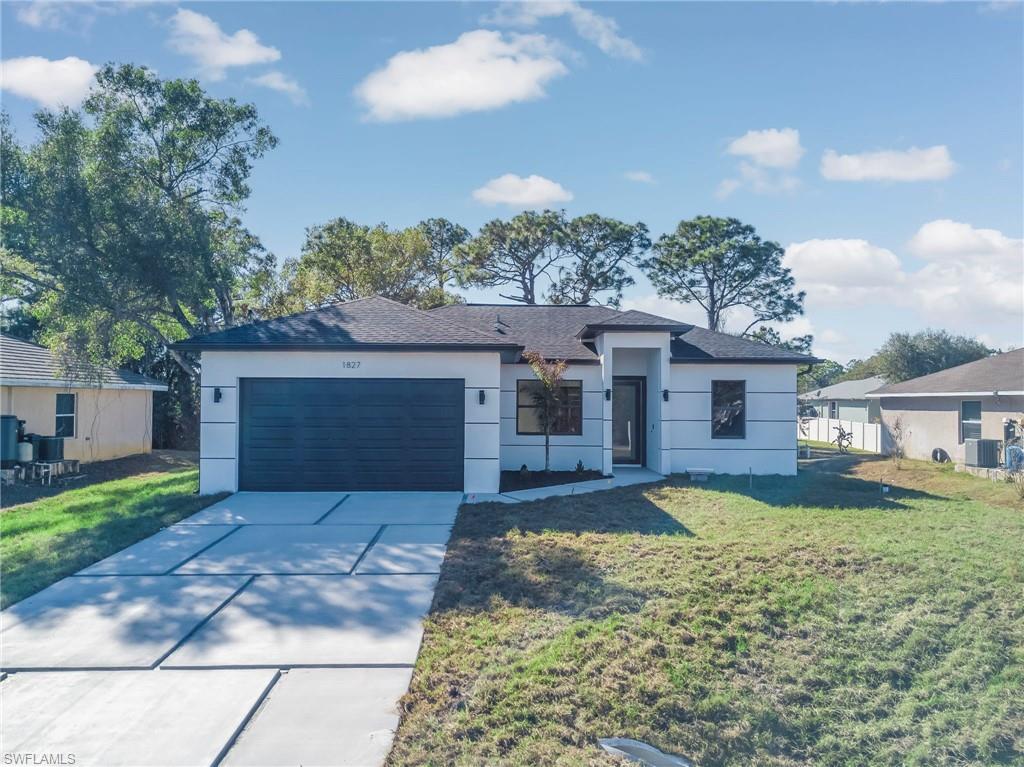 Single story home featuring a front lawn, an attached garage, driveway, and stucco siding