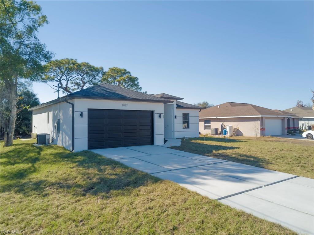 Ranch-style house featuring a front yard, a garage, driveway, and stucco siding