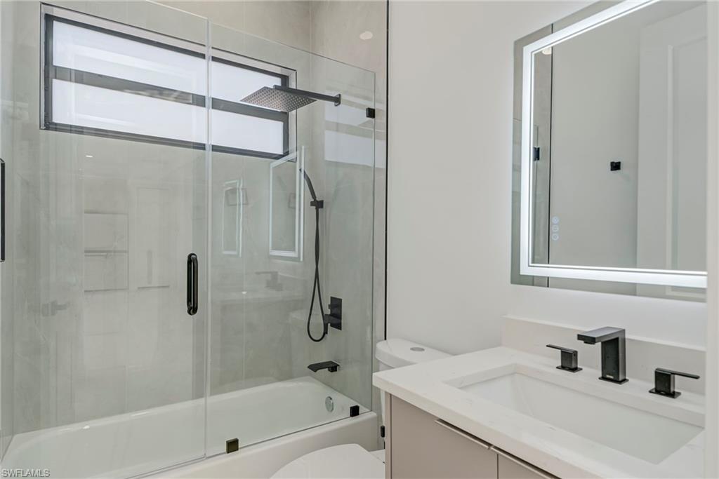 Full bath featuring vanity and shower / bath combination with glass door