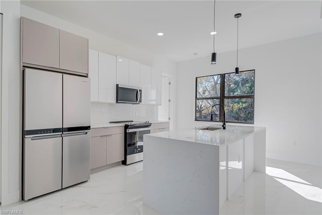 Kitchen with stainless steel appliances, hanging light fixtures, light marble finish flooring, modern cabinets, and light stone counters