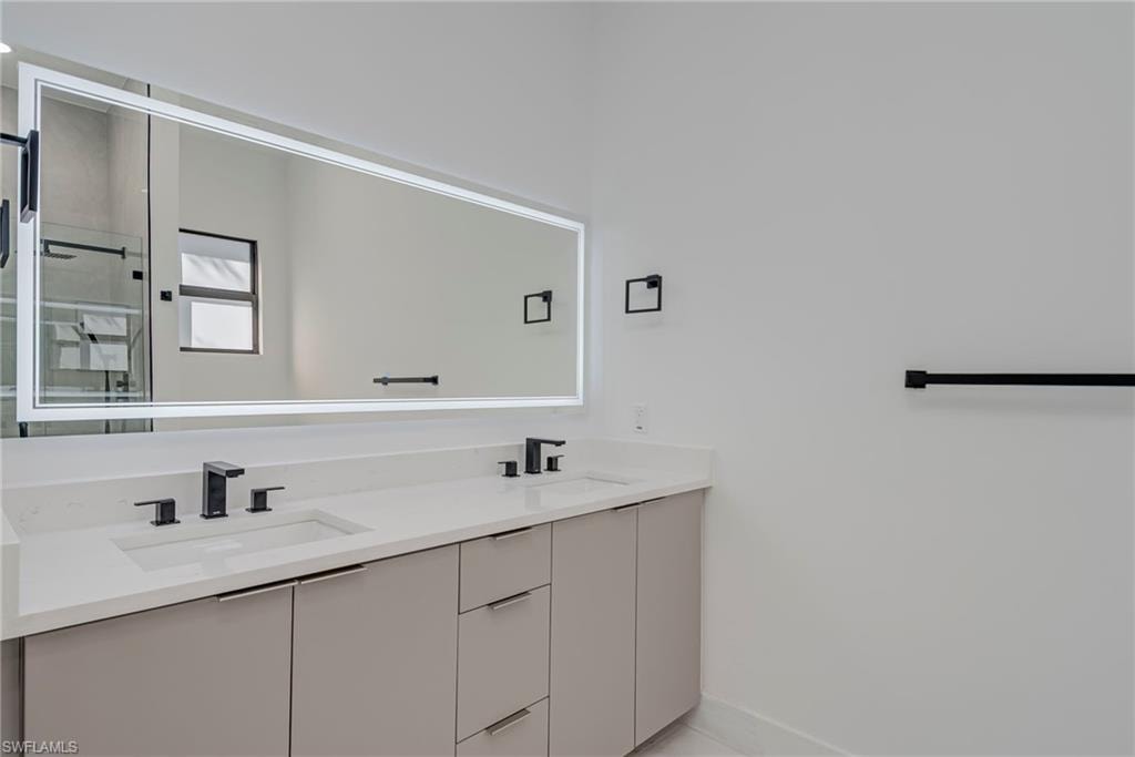 Full bathroom featuring double vanity and baseboards