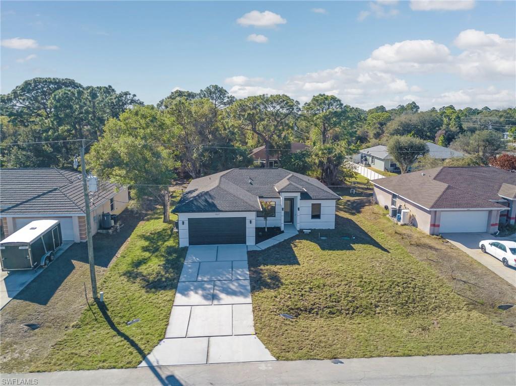 View of front of property featuring driveway, a front lawn, a garage, and a residential view