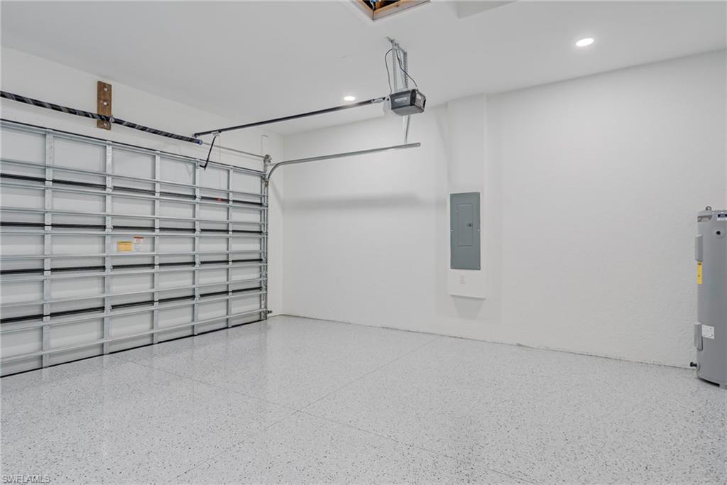 Garage featuring electric panel, recessed lighting, electric water heater, and a garage door opener