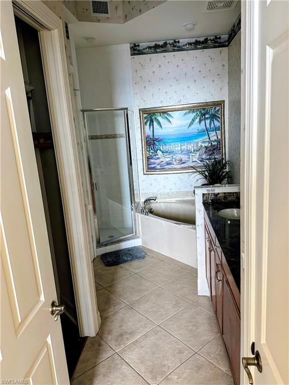Full bathroom with vanity, wallpapered walls, a bath, a shower stall, and light tile patterned floors
