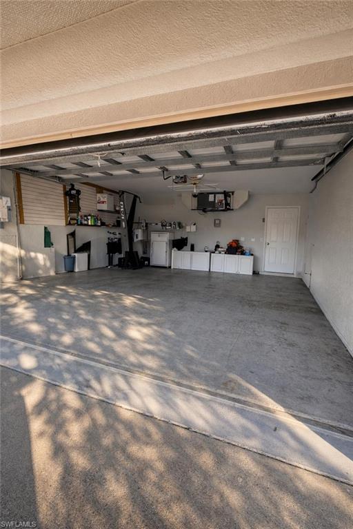 Garage with electric water heater, paneled built in fridge, and driveway