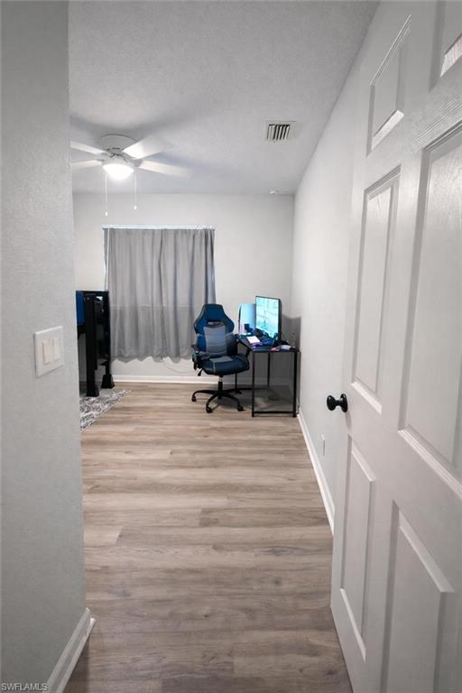 Office featuring wood finished floors, a ceiling fan, and a textured ceiling