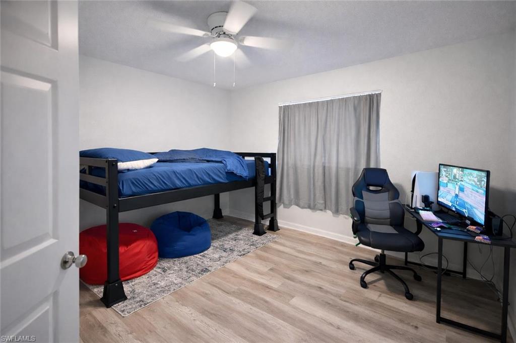 Bedroom featuring an office area, light wood-style floors, and a ceiling fan