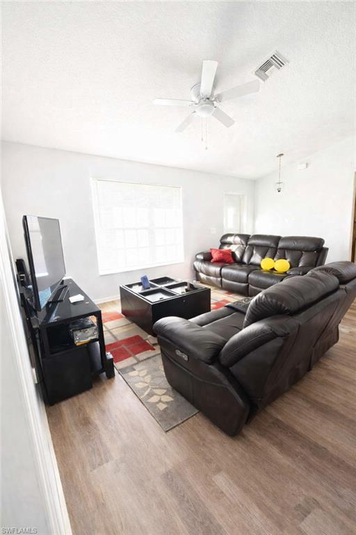 Living area featuring wood finished floors, a textured ceiling, and ceiling fan