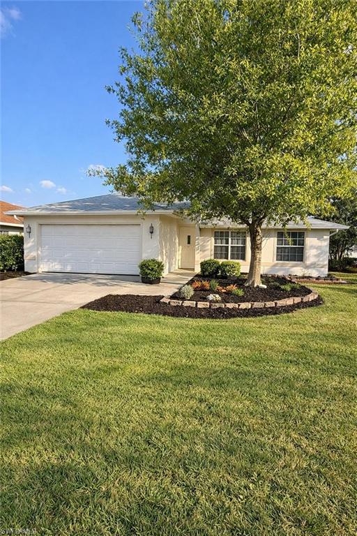 View of front facade with driveway, an attached garage, and a front yard