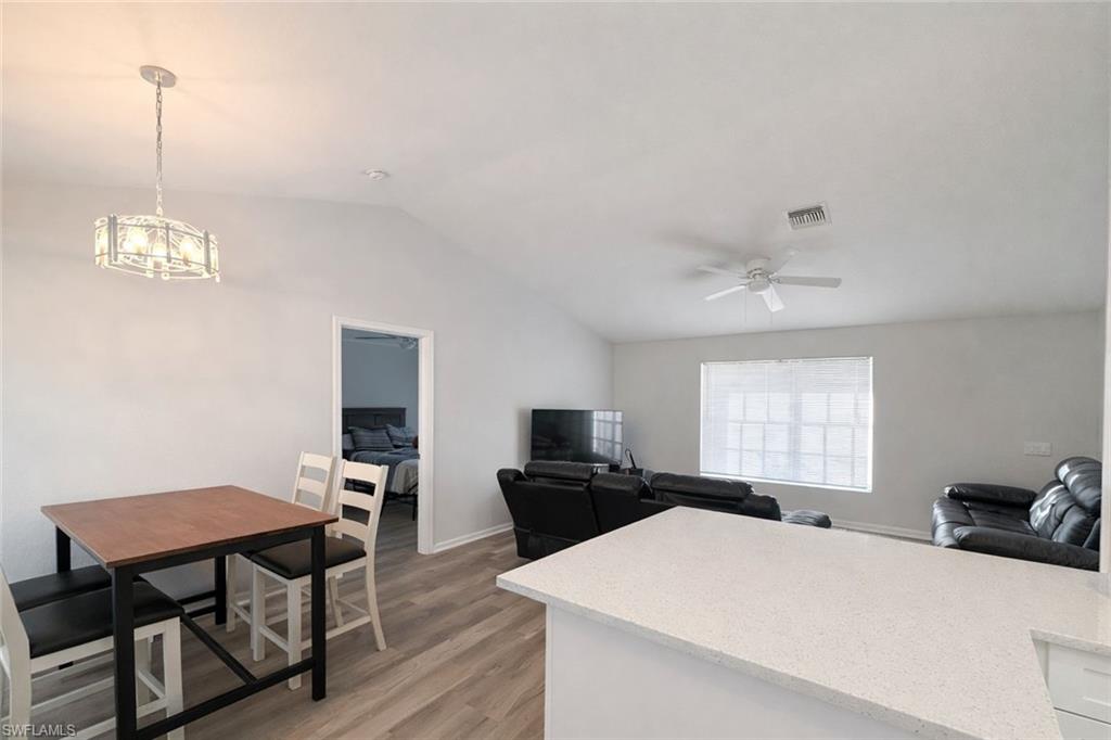 Kitchen featuring light stone countertops, light wood-type flooring, vaulted ceiling, and open floor plan