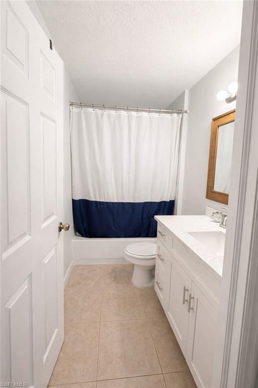Full bathroom with vanity, a textured ceiling, and light tile patterned flooring