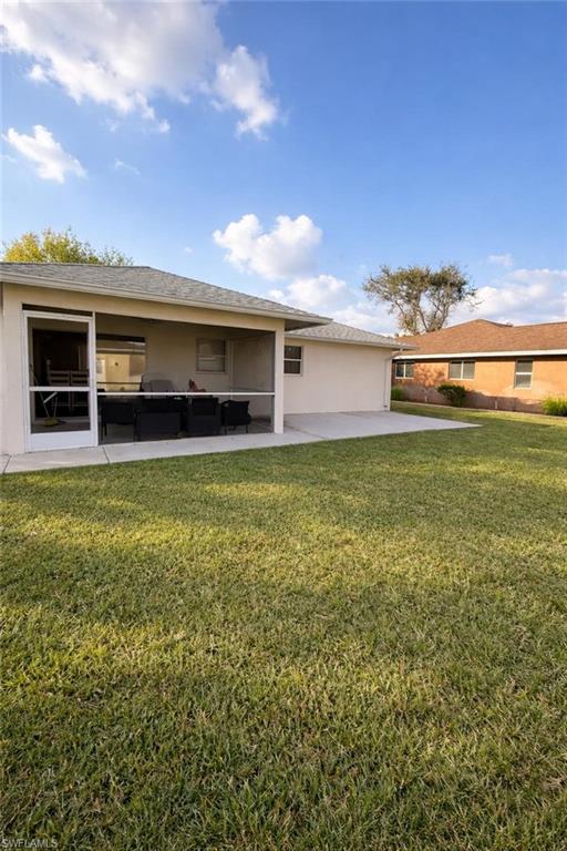Back of house featuring a lawn, stucco siding, a patio area, and an outdoor lounge area