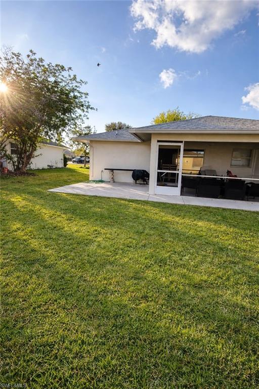 Back of house with a yard and stucco siding